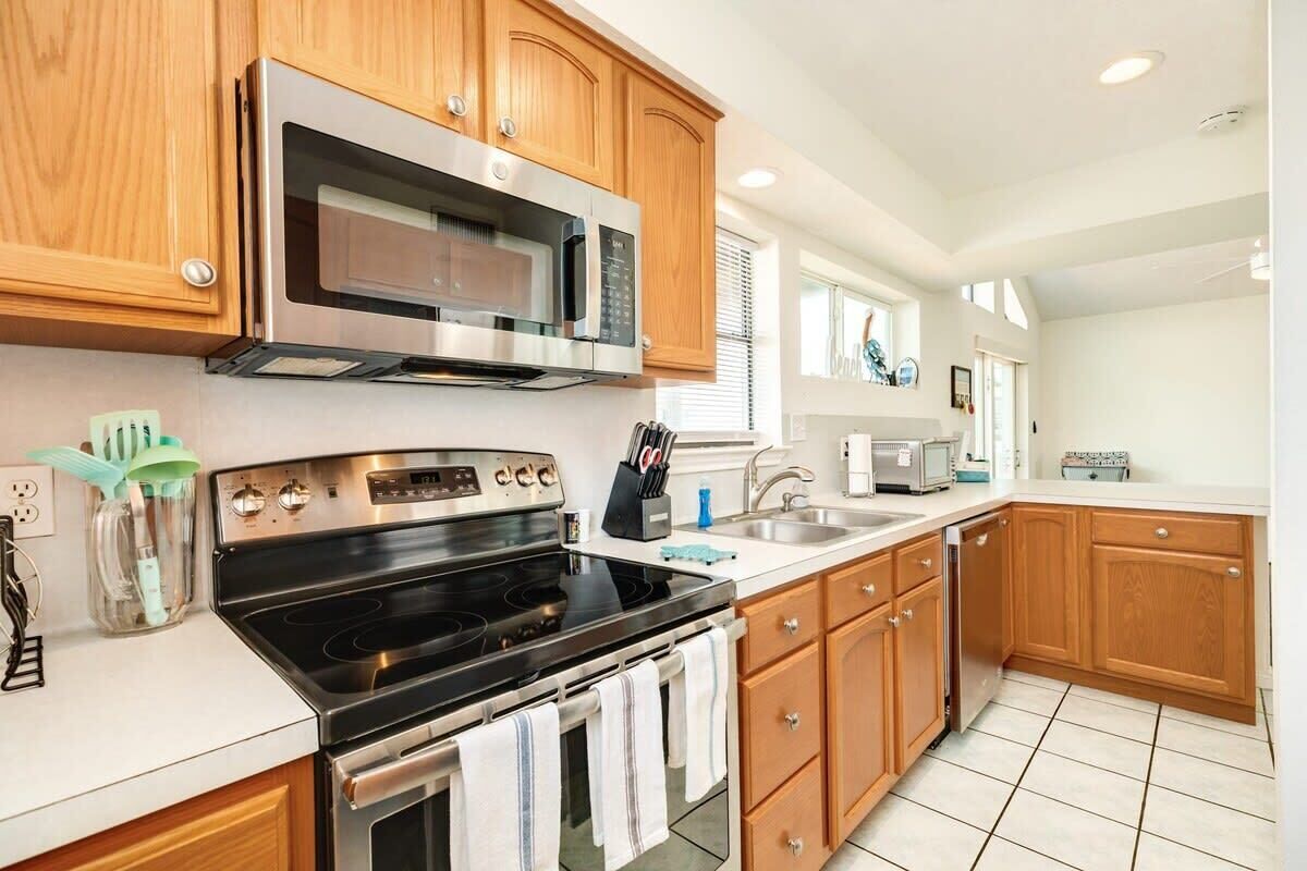 A modern kitchen with wooden cabinets, stainless steel appliances, and a tiled backsplash.