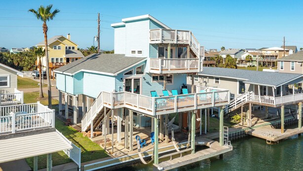 A waterfront property with multiple decks and a dock extending into the water. - Seas the Day - Penthouse-like views Gulf, Beach & Bay! (Galveston)
