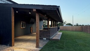 A covered outdoor patio with a stone bench, a wooden door, and a window. - Country Lodge (Great Bend)