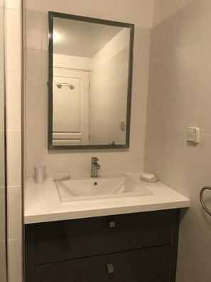 A bathroom with a white sink, a mirror, and a dark cabinet below.