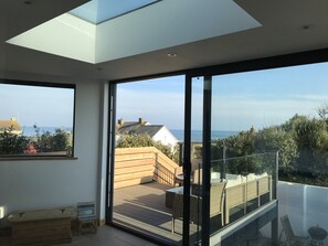 Ein modernes Interieur mit einer großen Schiebeglasdoor, die auf eine Terrassenanlage mit Möbeln führt.