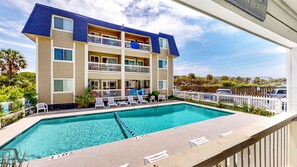 A hotel with a pool, multiple balconies, and a view of the surrounding area.