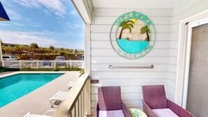 A poolside area with a pool, lounge chairs, and a decorative wall piece.