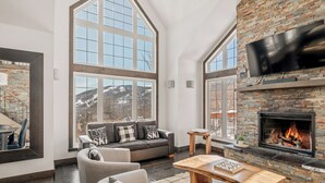 A spacious living room with a fireplace, large windows, and a cozy seating area. - 14- Cottage for rent in Stoneham  (CITQ: 245486) (Stoneham-et-Tewkesbury)