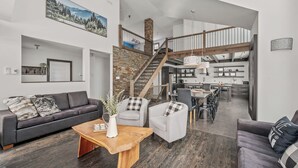 A spacious living area with a modern kitchen, a staircase leading to an upper level, and a dining area. - 14- Cottage for rent in Stoneham  (CITQ: 245486) (Stoneham-et-Tewkesbury)