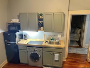 A compact kitchen with a built-in dishwasher, a microwave, and a washing machine. - 2/2 Apt downtown in restored historic home yr 1891 (Ocala)