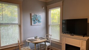 A living room with a fireplace, a television, and a dining table with chairs. - 2/2 Apt downtown in restored historic home yr 1891 (Ocala)