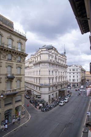 A street view with historic buildings, parked cars, and a few pedestrians. - AD Suites Tritone (Rome)