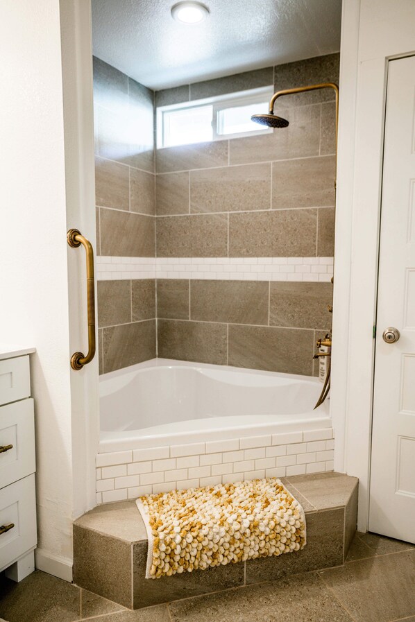 A bathroom with a bathtub, a shower, and a white door.