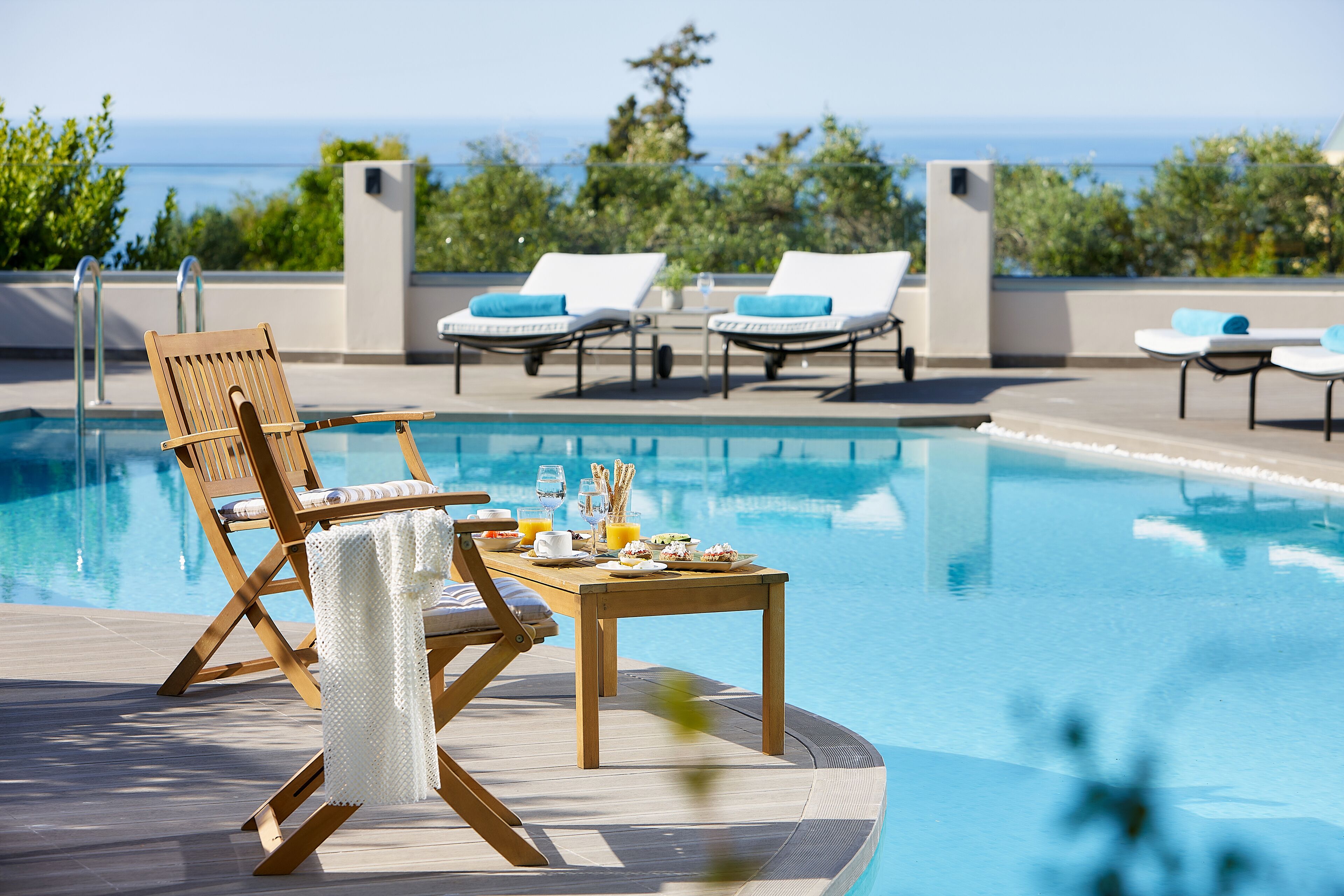 Ein Poolbereich mit Liegestühlen und einem Tisch, der für das Frühstück gedeckt ist.