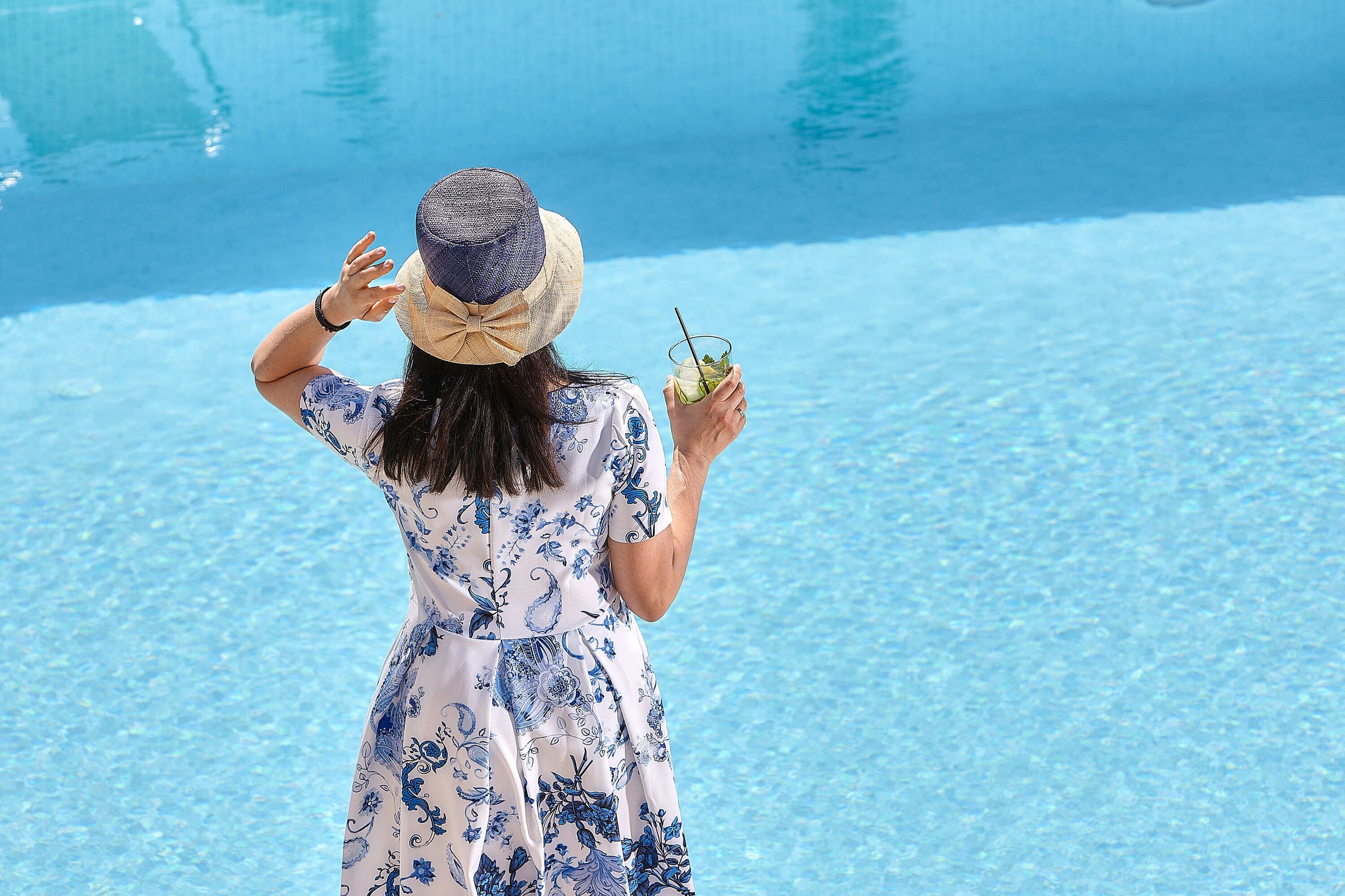 Eine Person in einem gemusterten Kleid steht an einem Pool.