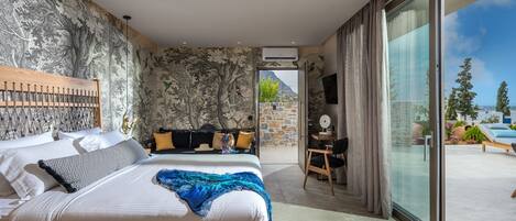A modern bedroom with a large bed, a desk, and a view of the outdoors.