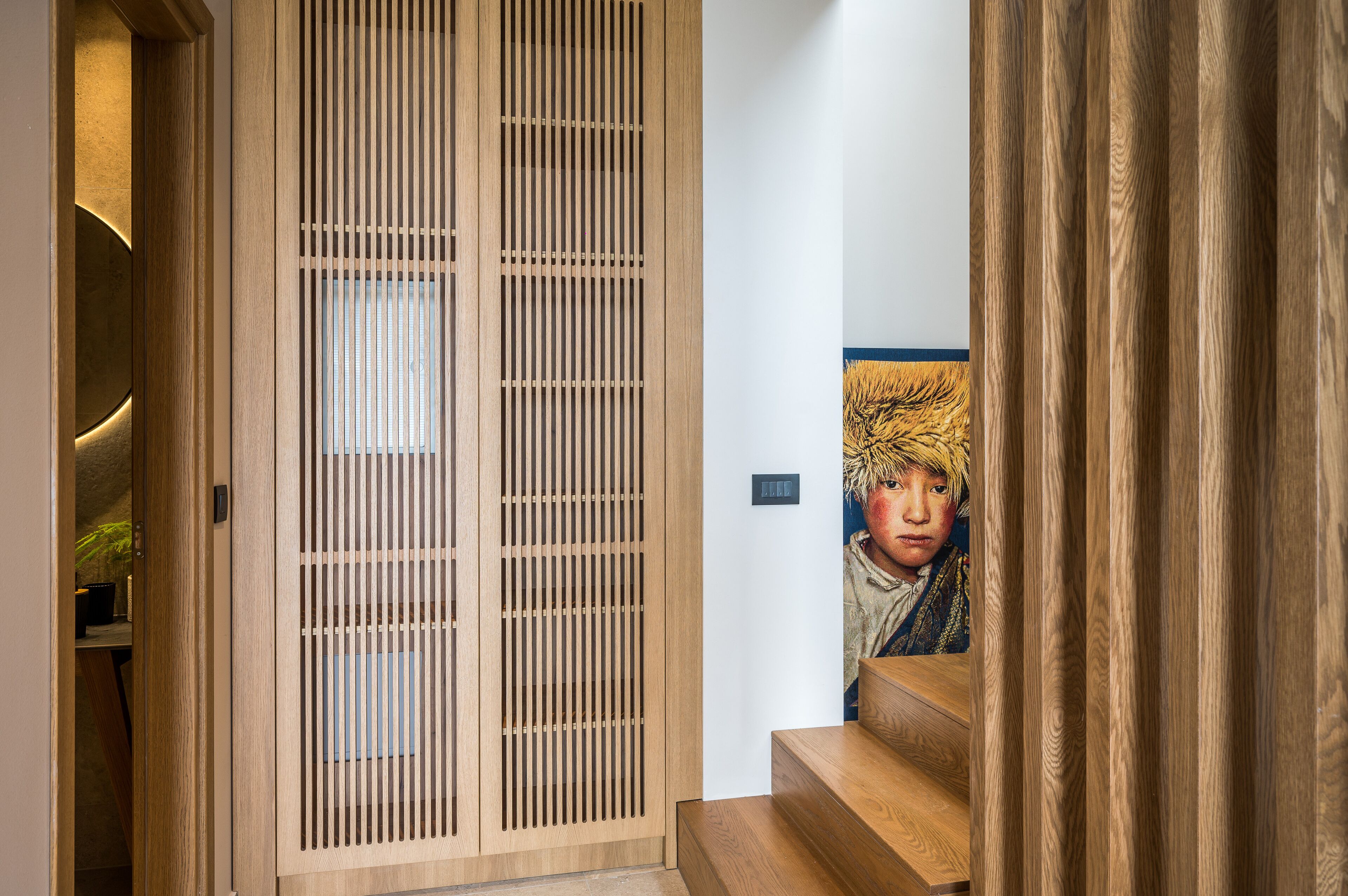 A wooden sliding door with vertical slats, a staircase with wooden steps, and a wall-mounted light fixture.