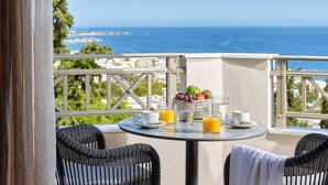A balcony with wicker chairs, a table with breakfast items, and a view of the sea. -  Grace Villas Collection (Hersonissos)