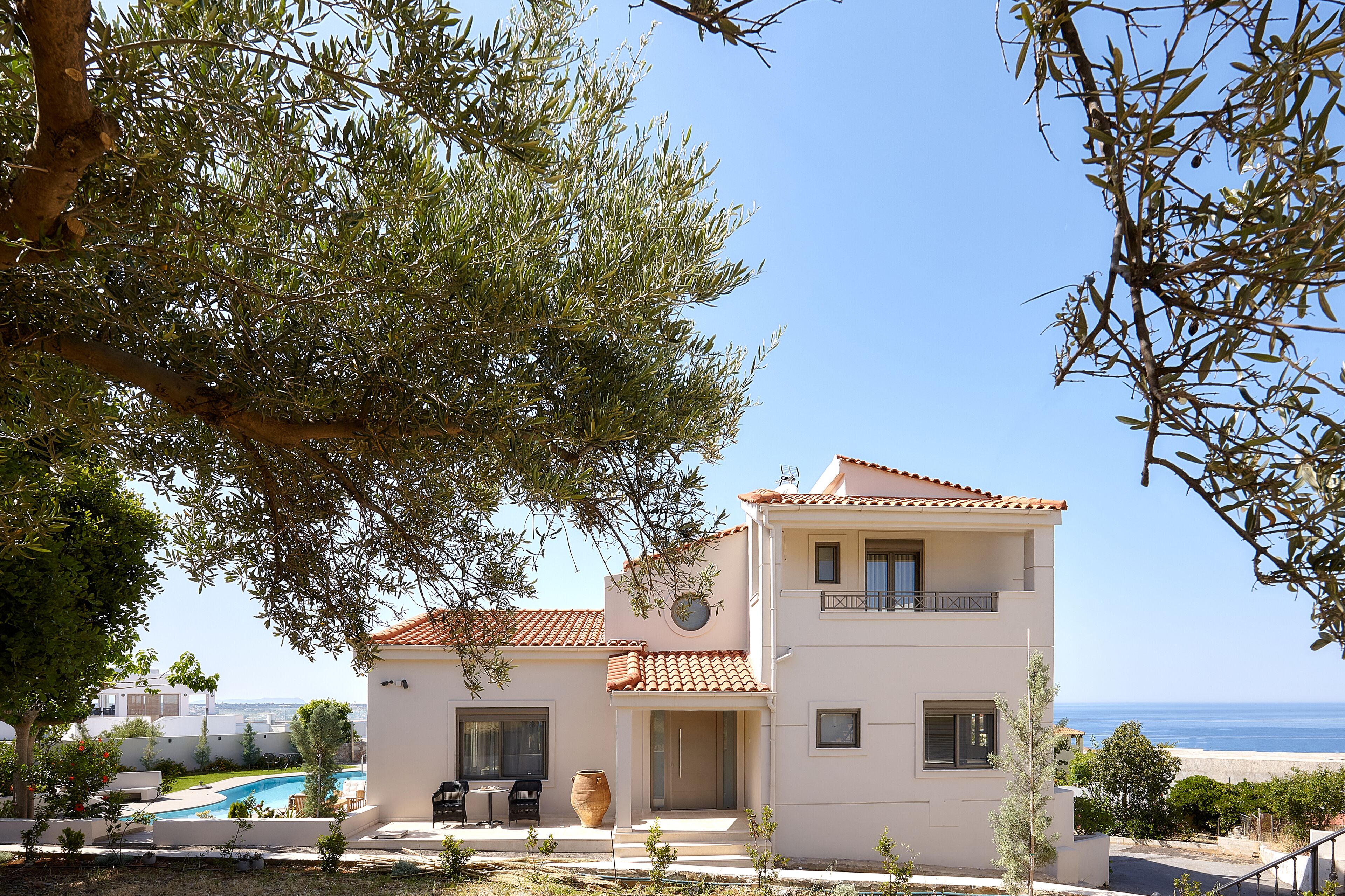 A two-story building with a swimming pool, a balcony, and a view of the sea.