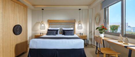 A modern bedroom with a large bed, bedside tables, a desk, and a view of the city through large windows.