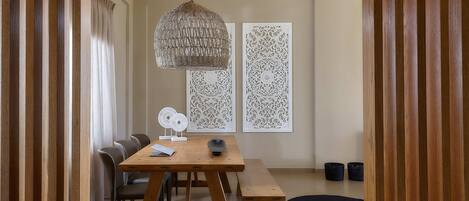 A dining area with a wooden table, chairs, a bench, a hanging light fixture, and decorative wall panels.