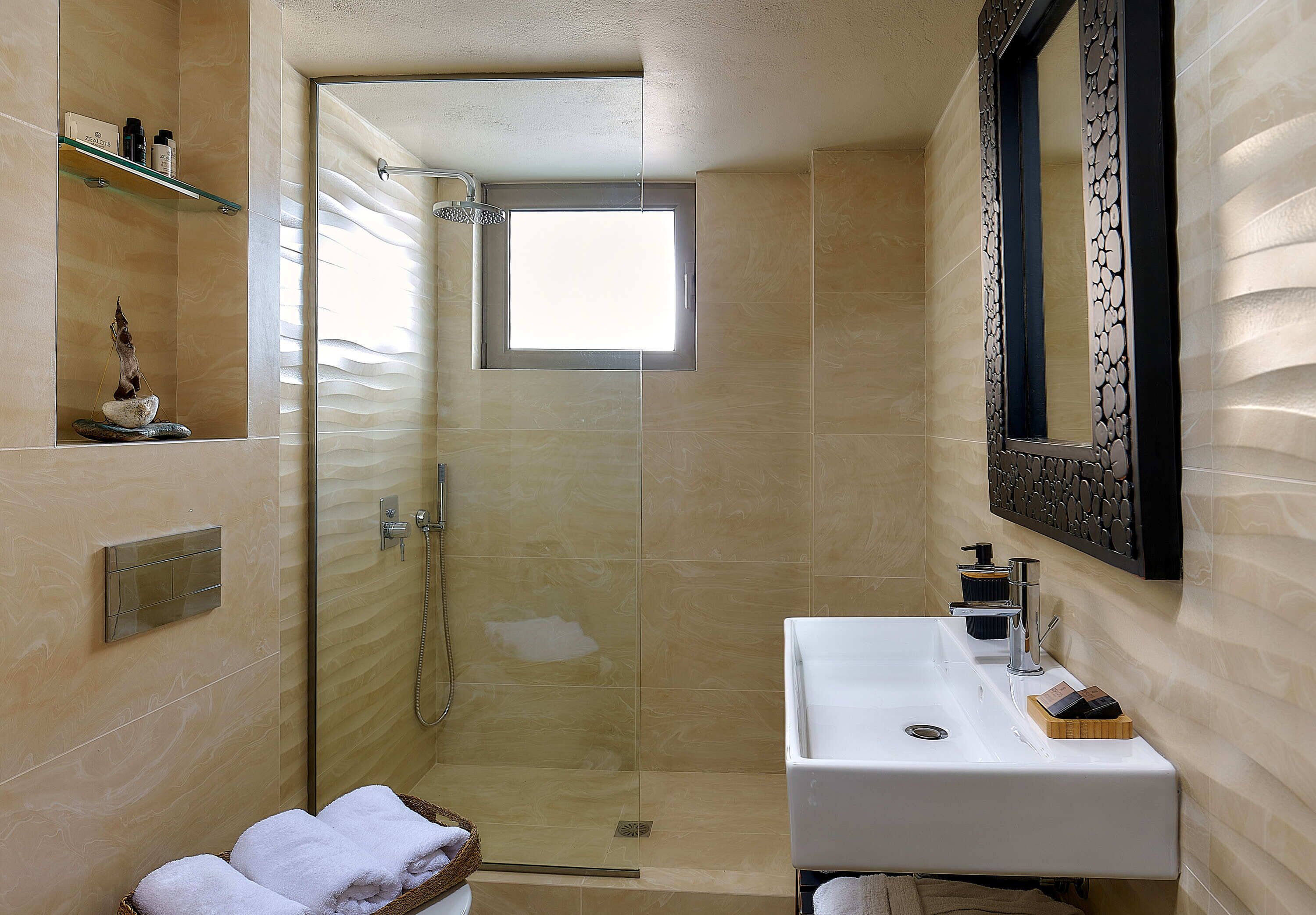 A modern bathroom with a glass-enclosed shower, a white sink, and a decorative mirror.