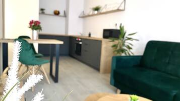 Een moderne keuken met een eethoek, een groene bank en een kleine tafel met een plant.