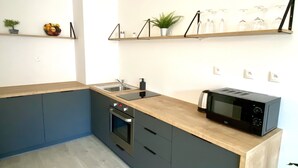 Eine moderne Küche mit Einbauofen, Mikrowelle und Spüle. Regale mit Pflanzen und Glasware sind vorhanden.