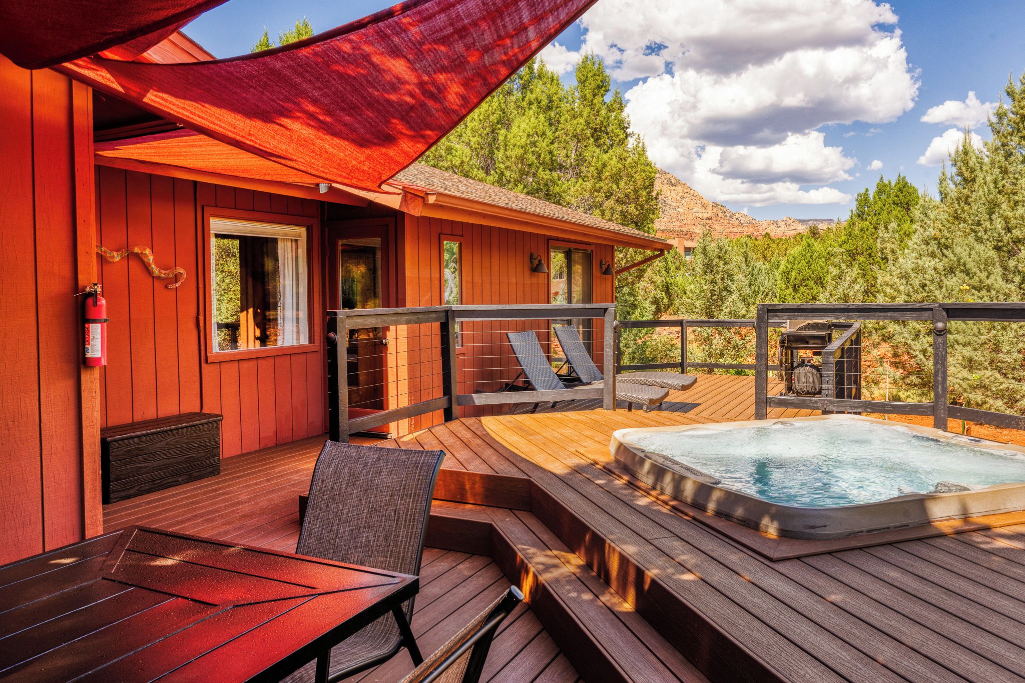Eine Holzterrasse mit Whirlpool, Liegestühlen und einem Tisch.