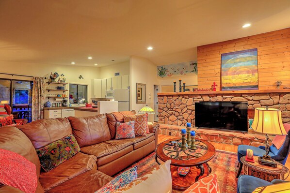 A cozy living room with a stone fireplace, a flat-screen TV, and a comfortable seating area.