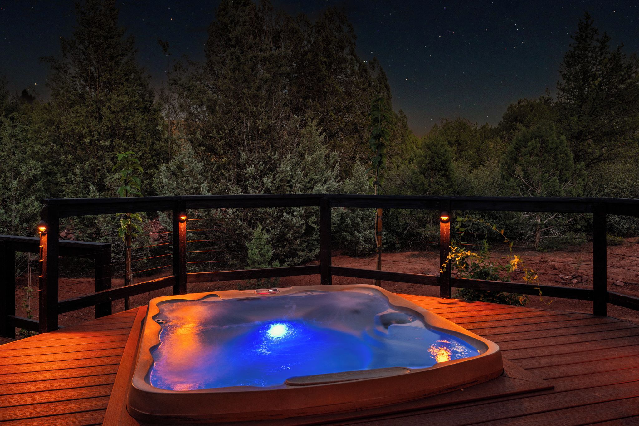 A hot tub on a wooden deck with a night sky view.
