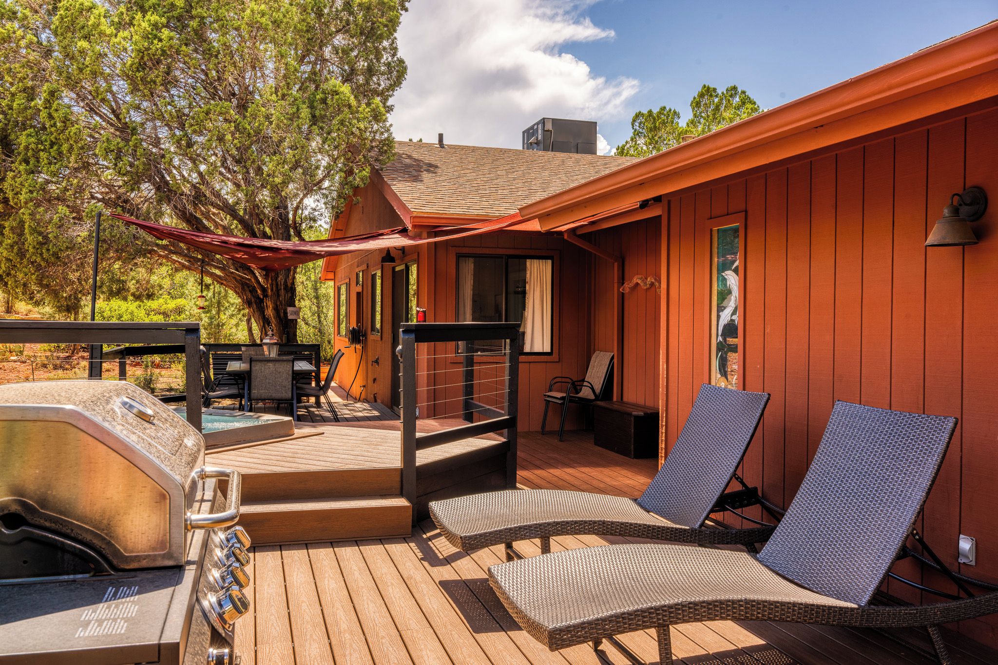 A wooden deck with outdoor furniture, a barbecue grill, and a covered seating area.