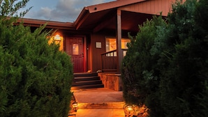 A wooden house with a red door, a stone pathway, and a 'Love Lives Here' sign. - Luxury Sedona Home with Finnish Sauna and Hot Tub (Sedona)