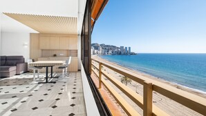 Un balcón con comedor, sofá y vistas a la playa y al paisaje urbano.