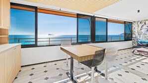 Un balcón con vista al mar, una mesa de madera y una silla.