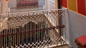 A staircase with a white railing leading to a red door, surrounded by walls with vertical stripes in red, yellow, and orange. - The Musician Angels (Sogliano Cavour)