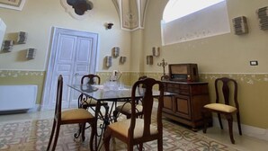 A dining area with a table, chairs, and a decorative ceiling. - The Musician Angels (Sogliano Cavour)