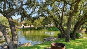 Um parque tranquilo com lago, árvores grandes e uma lareira.