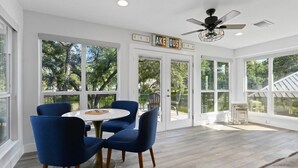 Quarto amplo e iluminado, com janelas grandes, ventilador de teto e uma placa com a inscrição 'LAKE HOUSE'.
