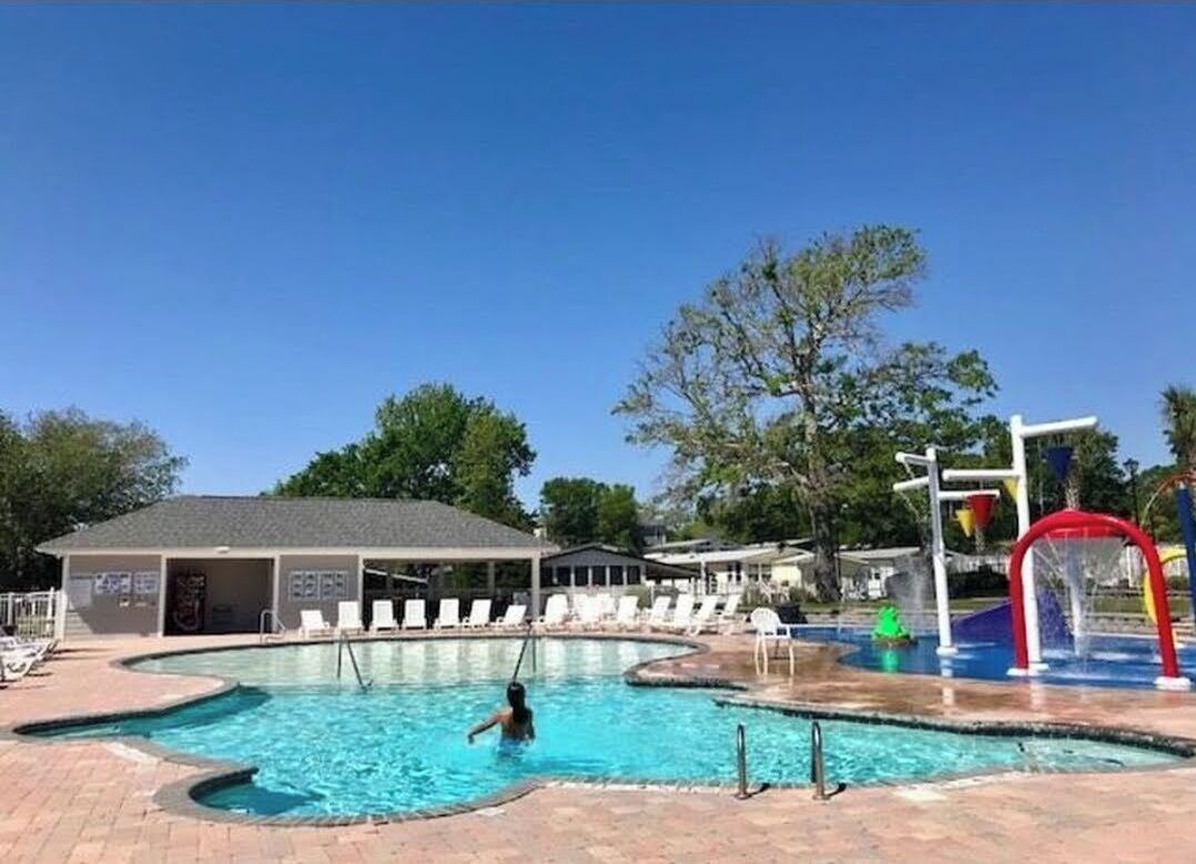 Una piscina con tobogán y sillas de descanso.