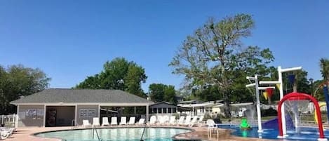 A swimming pool with a water slide and lounge chairs.