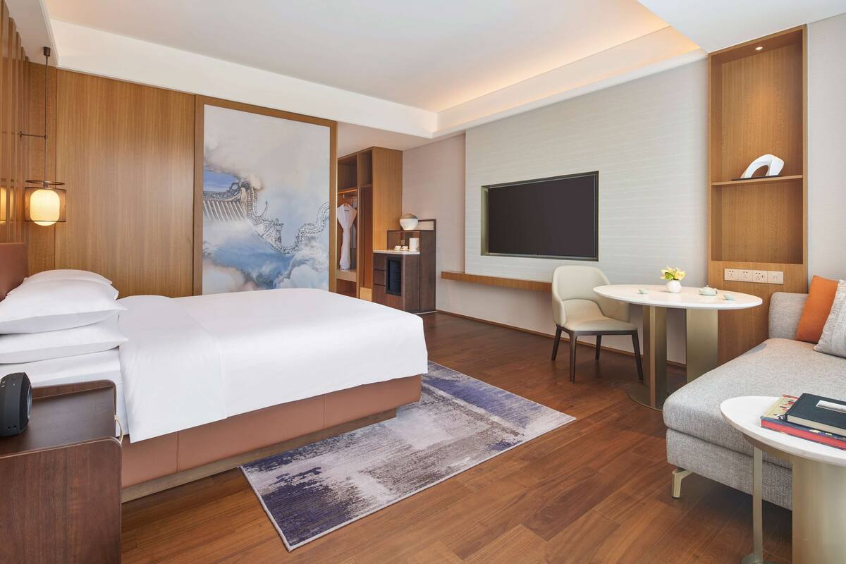 Une chambre d’hôtel moderne équipée d’un grand lit, d’un canapé, d’un bureau et d’une télévision.