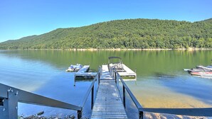 A wooden dock extending into calm water with boats docked at the end.