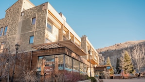 A modern building with a stone facade, large windows, and a wooden entrance.