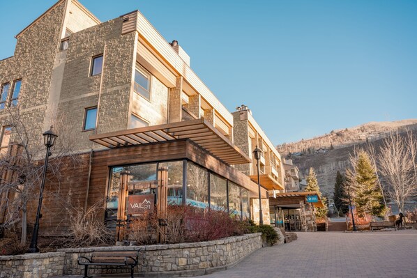 A multi-story building with a stone facade, large windows, and a wooden overhang.