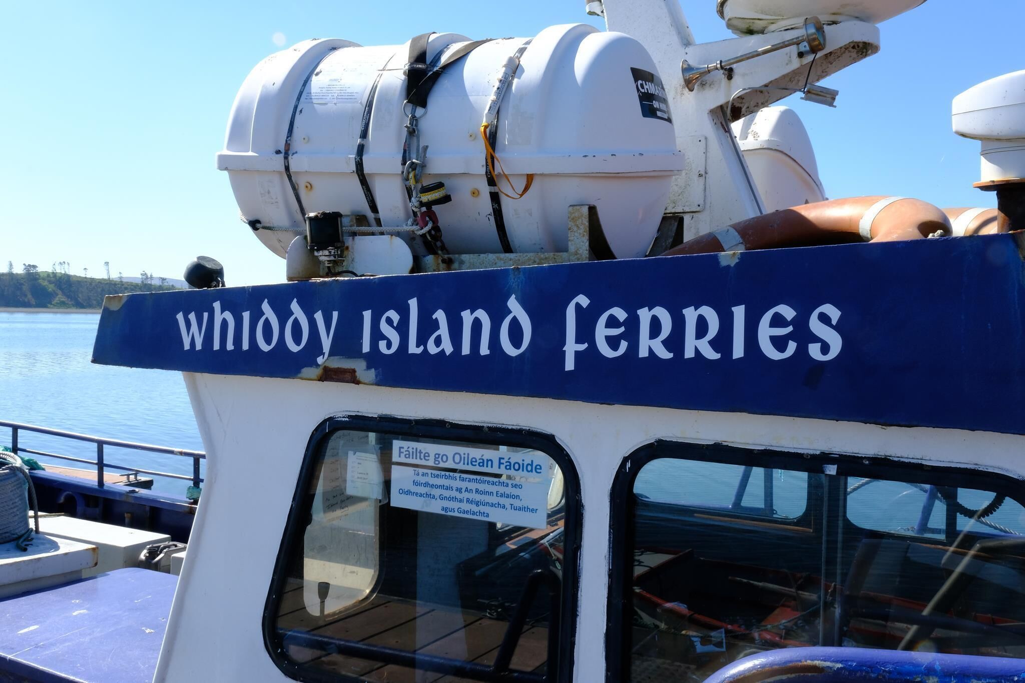 A ferry with a sign reading 'Whiddy Island Ferries' and a smaller sign in Irish.