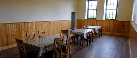 A dining area with wooden paneled walls, a high ceiling, and large windows.