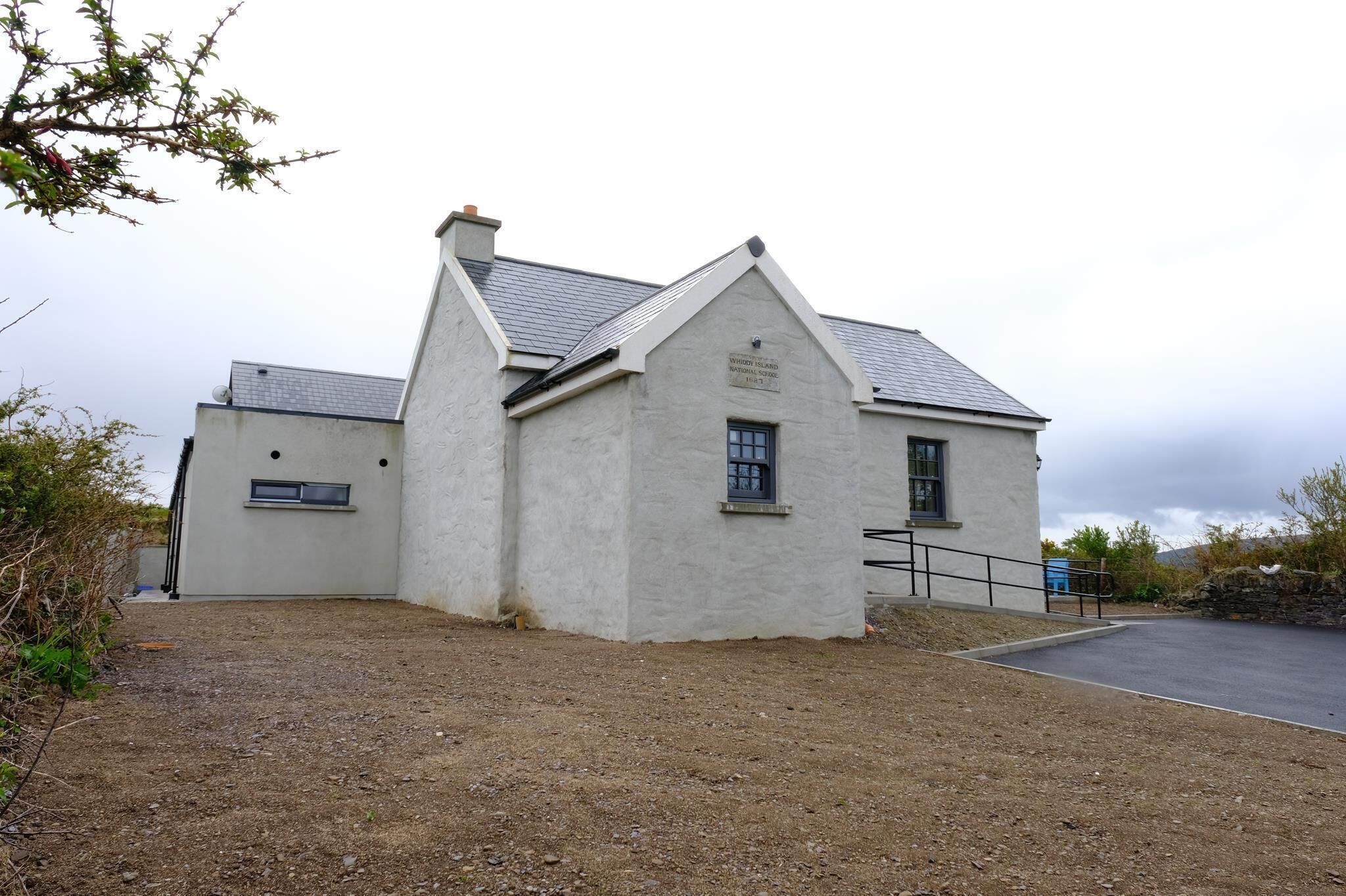 Un bâtiment à deux étages, doté d’un toit à pignon, d’une enseigne indiquant qu’il s’agit d’une école nationale, et d’une allée gravillonnée.