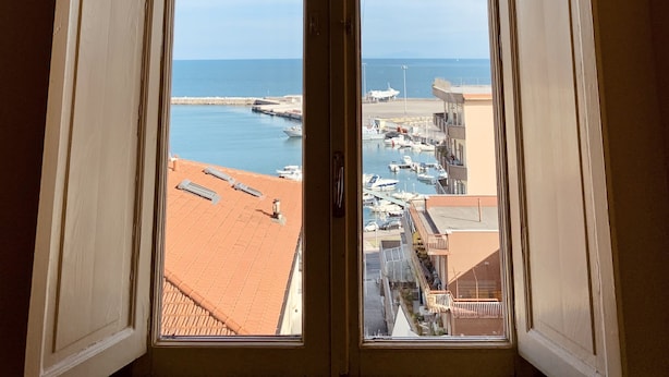 Vista a través de una ventana de arco, con vista a un puerto deportivo con barcos y edificios.