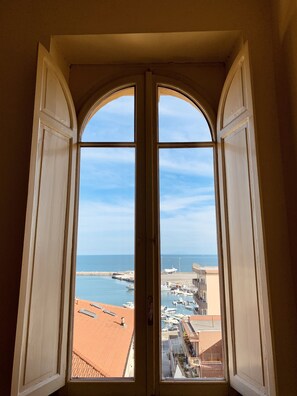 Une vue à travers une fenêtre à arc, donnant sur une marina avec des bateaux et des bâtiments.