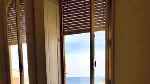 Una habitación con sofá blanco, un radiador y una ventana con persianas.