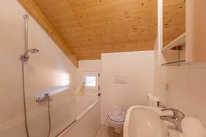 Ein Badezimmer mit Holzboden, einer Badewanne, einer Toilette und einem Waschbecken.