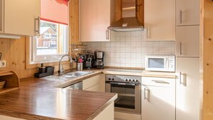 A modern kitchen with wooden cabinets, a stainless steel range hood, a microwave, and a dishwasher.