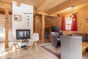 Cozy cabin living area with a sofa, chairs, flat-screen TV, and fireplace.